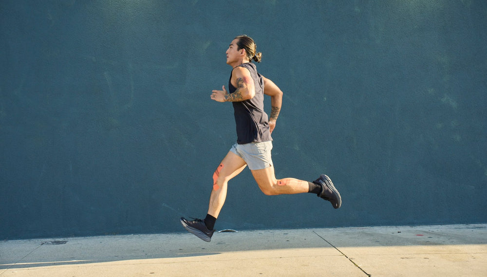 Man running on sidewalk with KT Tape on leg